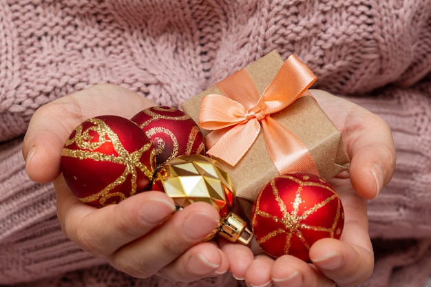 Hands in a knitted sweater holding gift present box. Christmas holidays preparation concept.