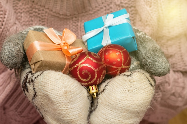 Foto mani in un maglione lavorato a maglia guanti tenendo presente confezione regalo. concetto di preparazione vacanze di natale.