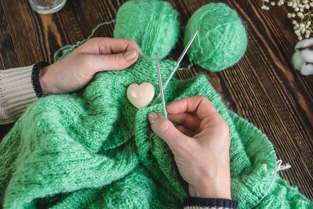 Hands knitting a cozy green sweater