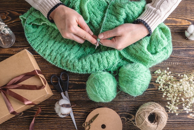 Hands knitting a cozy green sweater