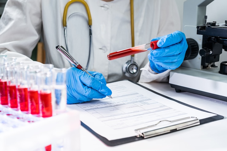 Photo hands of a lab technician with a tube of blood sample and a rack with other samples
