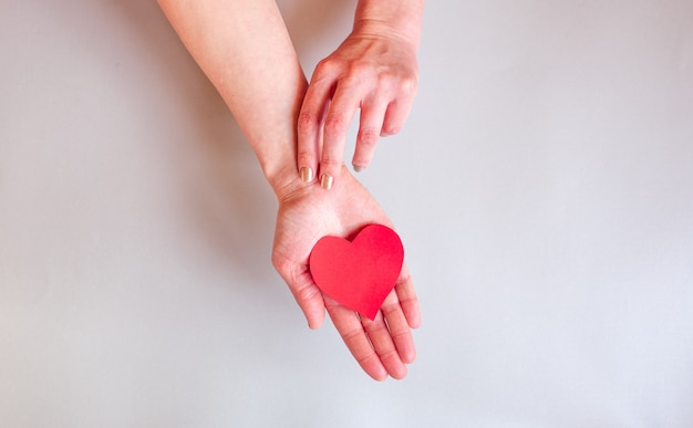 The hands of a lady holding a heart over surface,