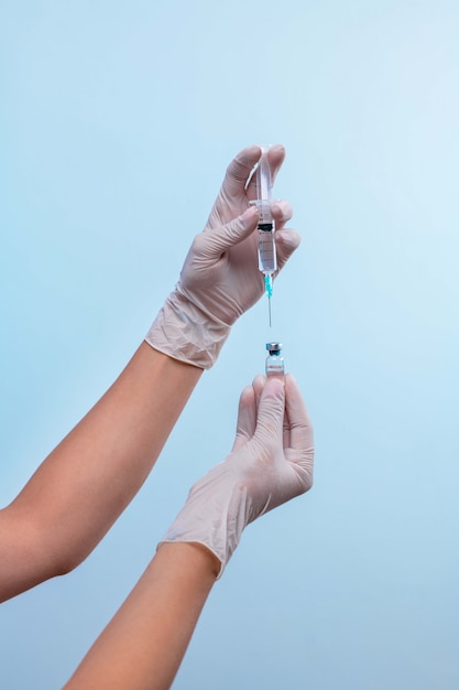 Hands in latex gloves collect medicine from an ampoule. The concept of pharmacology. 