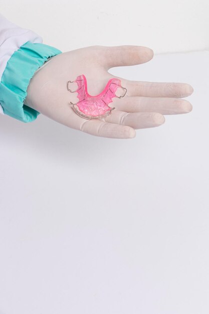 Hands in latex gloves with pink retainer