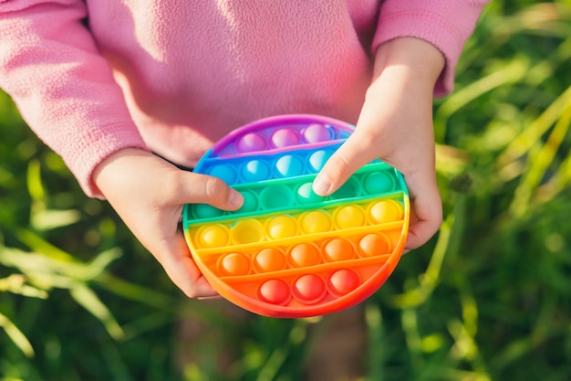 hands little girl holding antistress toy pop it standing outdoors in nature