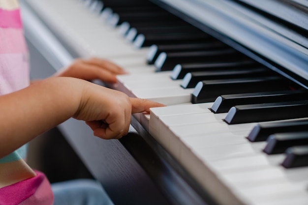 Hands of little girl playing piano selective focus