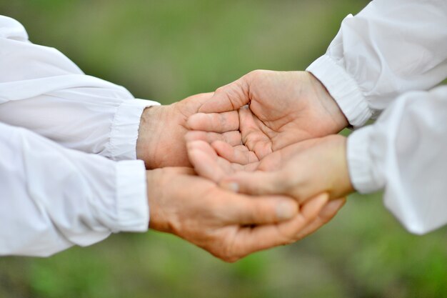 Hands of a loving couple on a background of autumn leaves