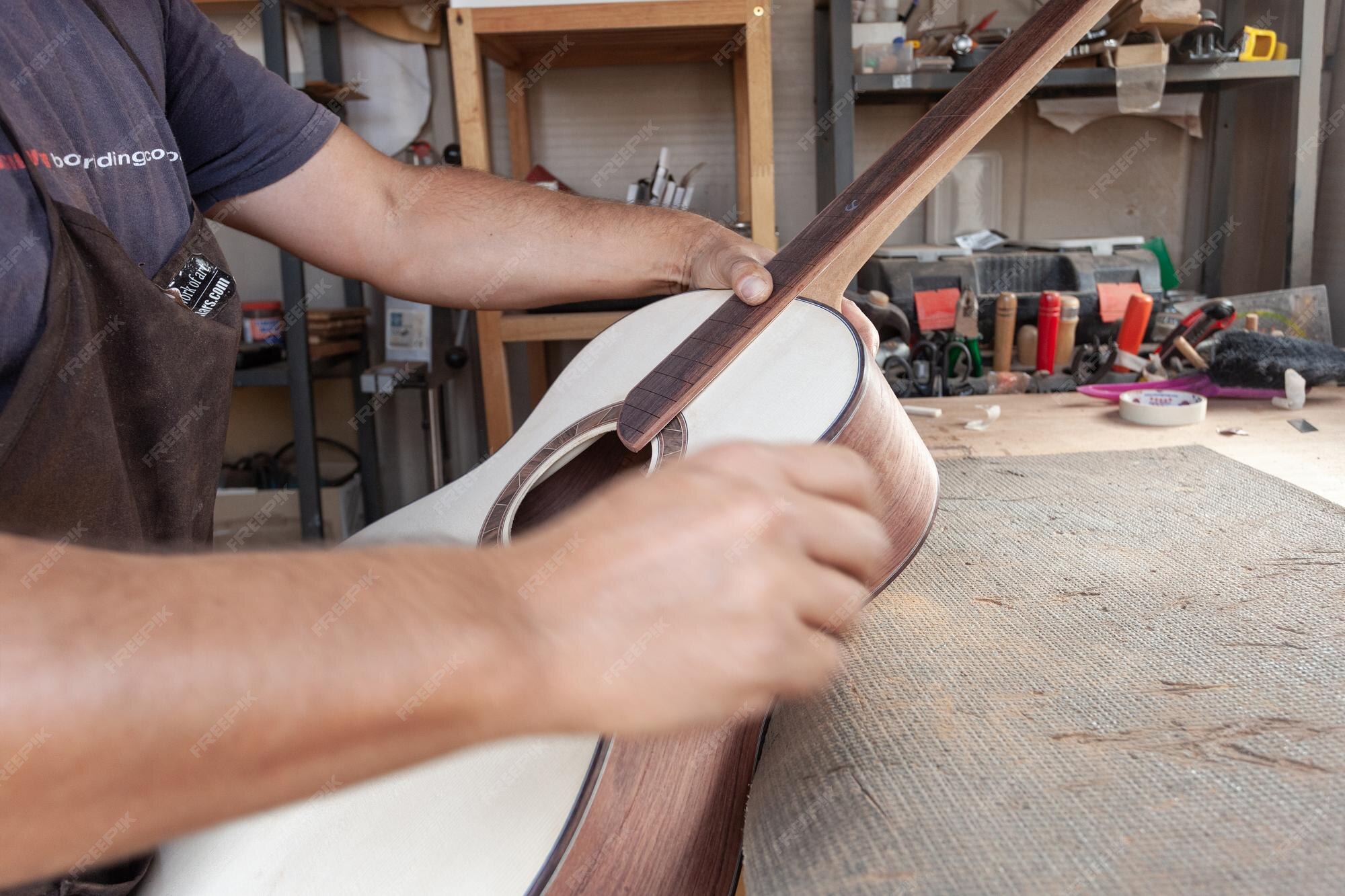 Premium Photo Hands of luthier sanding guitar neck