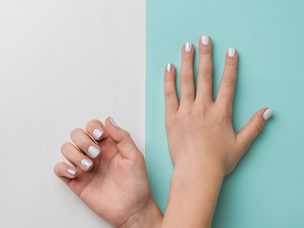 Hands lying on top of each other with stylish makeup on a blue and white surface