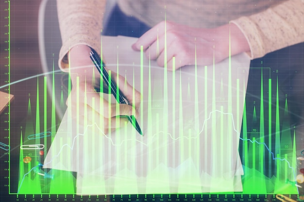 Hands macking notes in notepad Forex chart holograms in front Concept of research Multi exposure