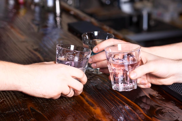 Hands make cheers with glasses of vodka