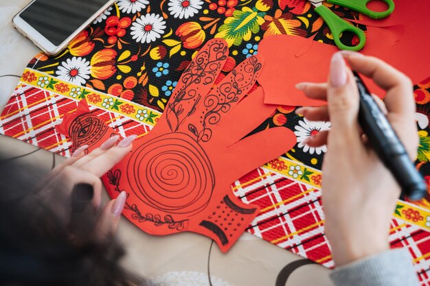 hands make crafts from colored paper at the table