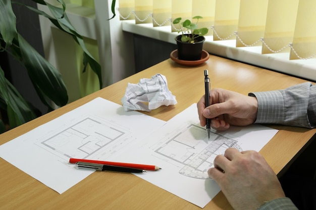 Hands make notes and measurements in architectural floor plan