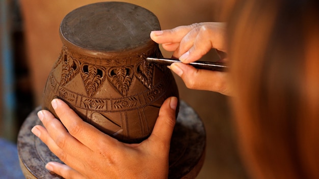 Hands make potter a decorative pattern on earthenware