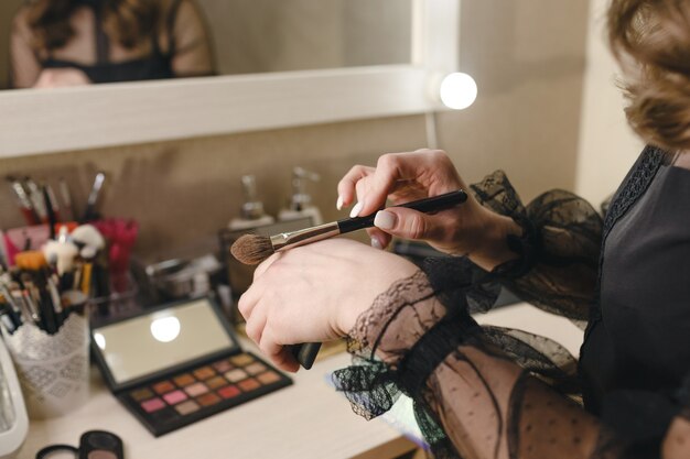 The hands of the make-up artist girl close-up hold a makeup brush. Self-care