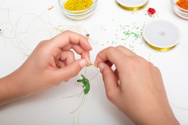 Hands making beads and wire jewelry