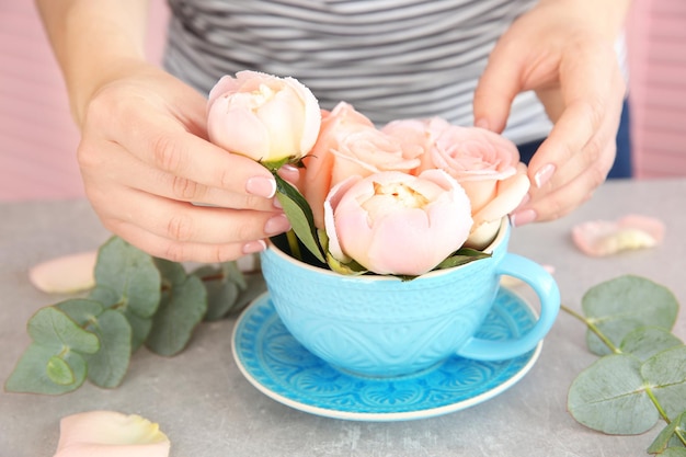 Hands making bouquet of flowers on a grey table