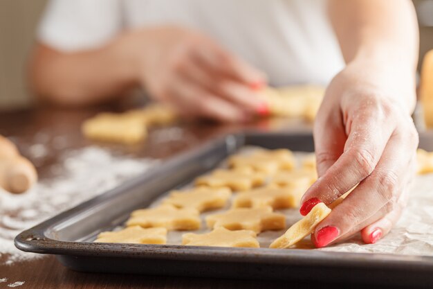 Hands making christmas cookies with metal cutter