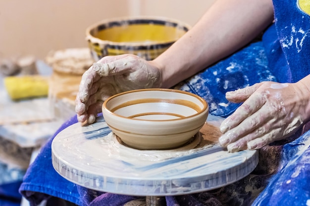 Hands making a clay bowl on a potter's wheel