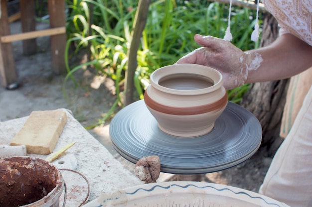 Hands of making clay pot on the pottery wheel