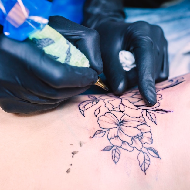 Photo hands making flower tattoo with needle