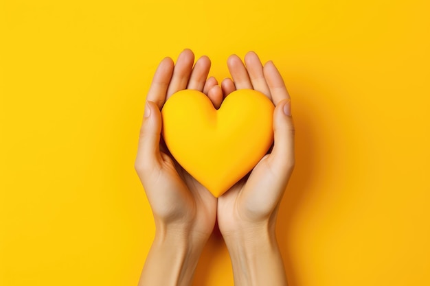 Hands making heart shape isolated on a yellow background