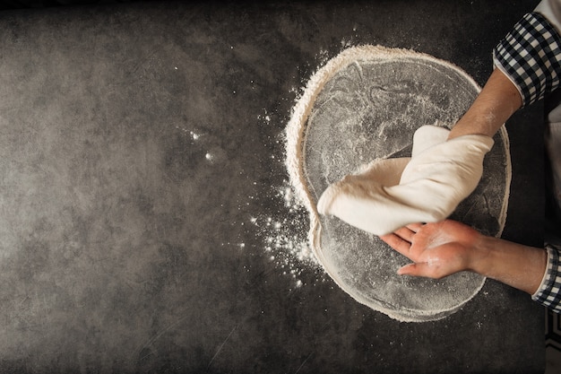 Hands making a pizza dough with flour