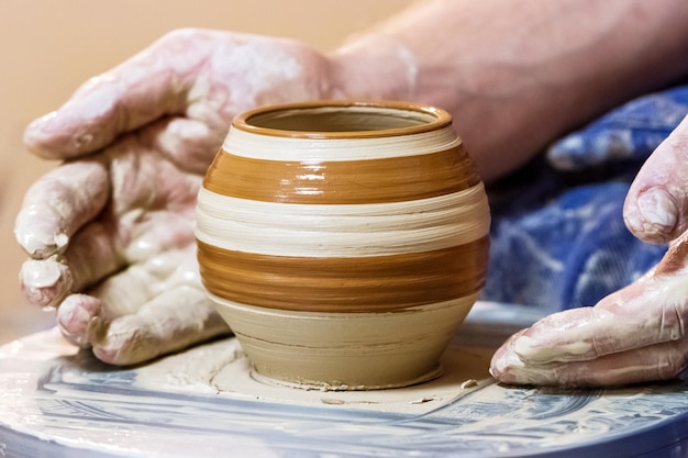 Hands making a pot on a potter's wheel