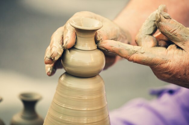 Hands making pottery on a wheel