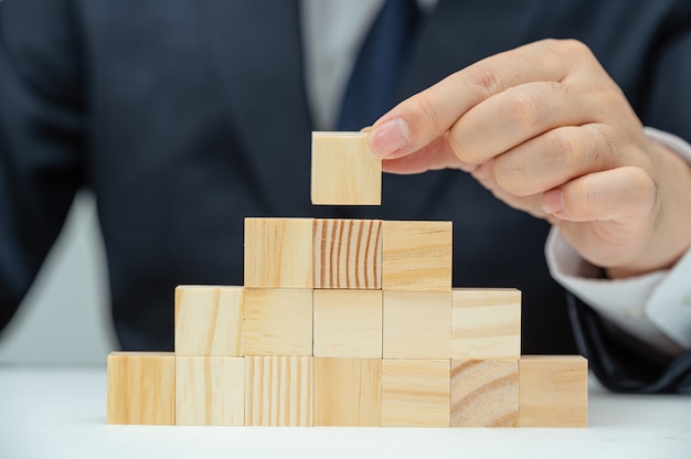 Le mani di un uomo d'affari che sta impilando blocchi di legno. concetto di affari.