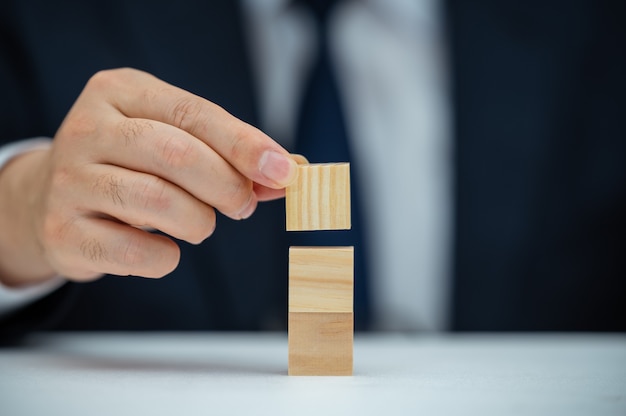 The hands of a male businessman who is stacking wooden blocks. Business concept.