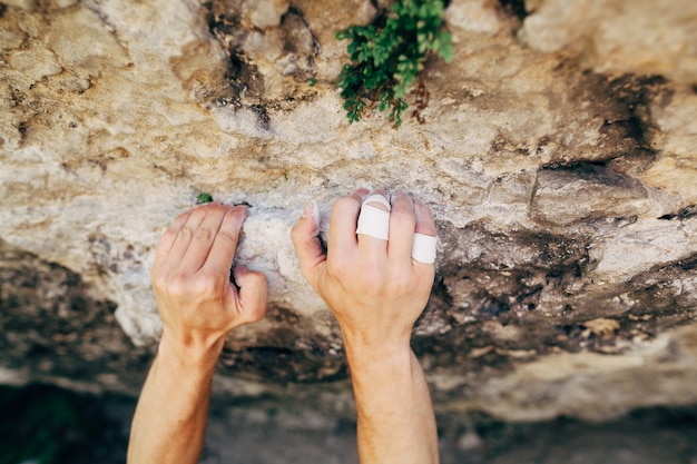 Hands of the male rock climber hanging on the cliff