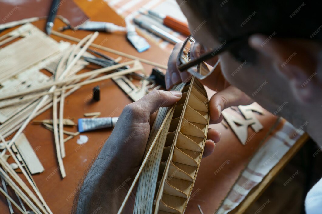 Premium Photo Hands of man gluing plywood details for ship model with glue holding with