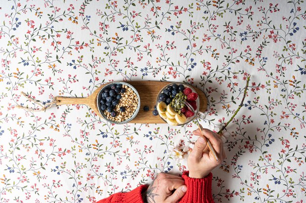 The hands of a man having breakfast in bed a cup of yogurt with fruits