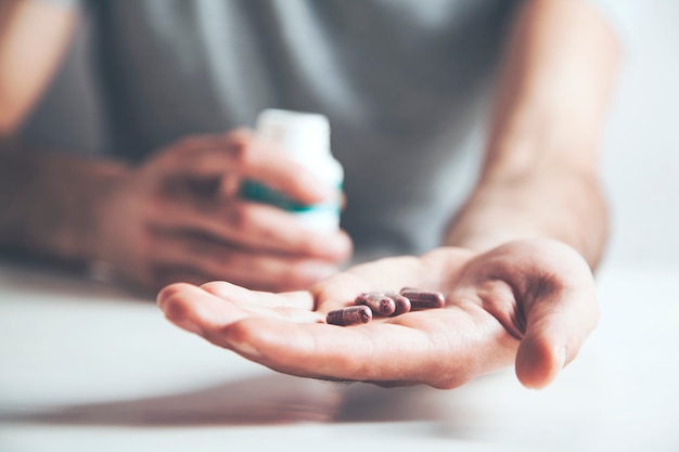 Hands of man holding pill bottle with pills on hand