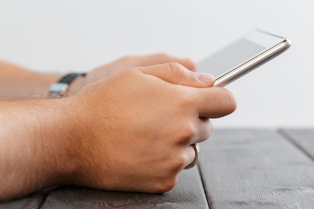 Hands of a man holding tablet device over a wooden workspace table