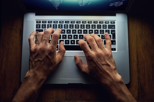 サイバー犯罪の手とノートパソコンデータベースソフトウェアと詐欺のハッキングマルウェアとスパムをプログラミングする人フィッシングのシステムまたはアルゴリズム盗賊と情報のコーディングスクリプト