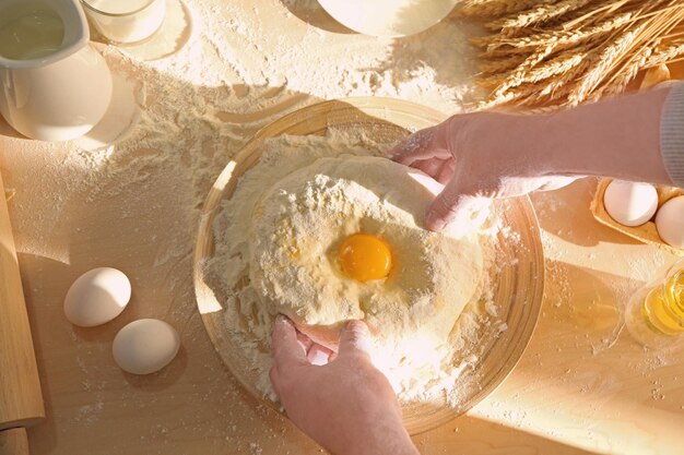 Hands of man making dough in kitchen