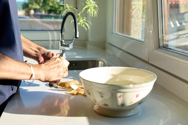 Hands of a man peeling potatoes in the kitchen, no faces shown, man cooking concept