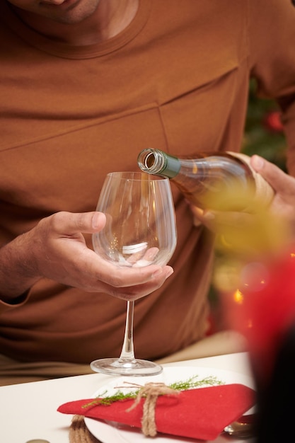 Hands of man pouring champagne in glass at dinner table