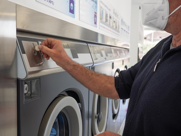 Hands of man selecting coins for washing machine at laundrette. Cleaning concept