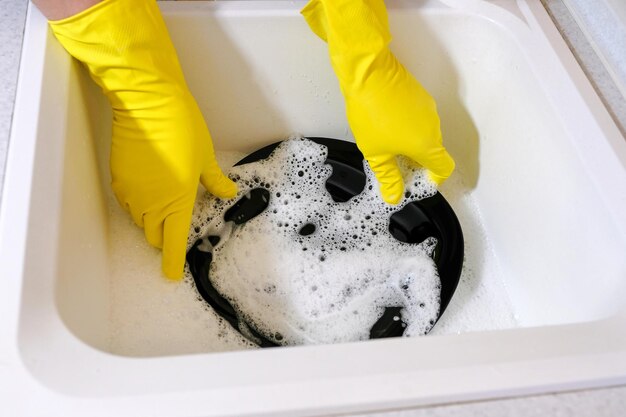 Hands of a man washing dishes in the sink homework in the\
kitchen