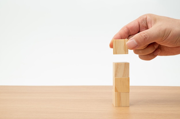 Le mani di un uomo che sta impilando il concetto di affari dei blocchi di legno