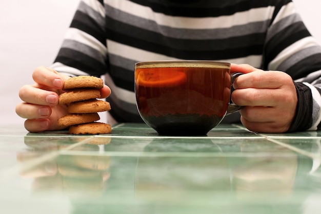 Hands of a man with a cup of tea and biscuits