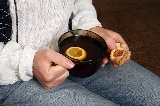 Hands of a man with a cup of tea and biscuits