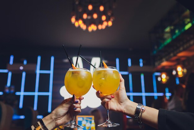 Photo hands of man and woman cheering with glasses of pink champagne