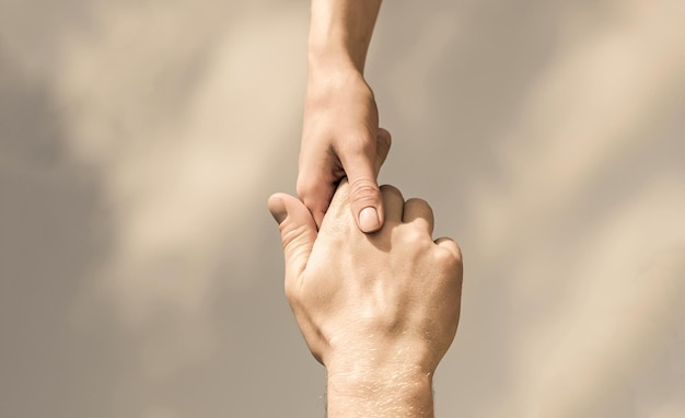 Hands of man and woman reaching to each other support Solidarity compassion and charity rescue Giving a helping hand Hands of man and woman on blue sky background Lending a helping hand