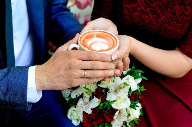 Hands man and woman with a cup of coffee with heart