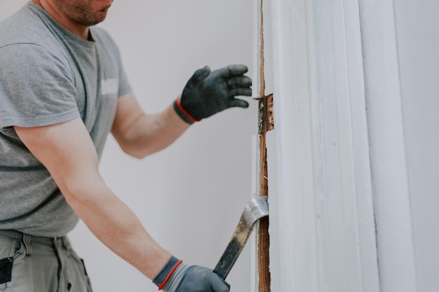 Hands of a man working with a crowbar indoors