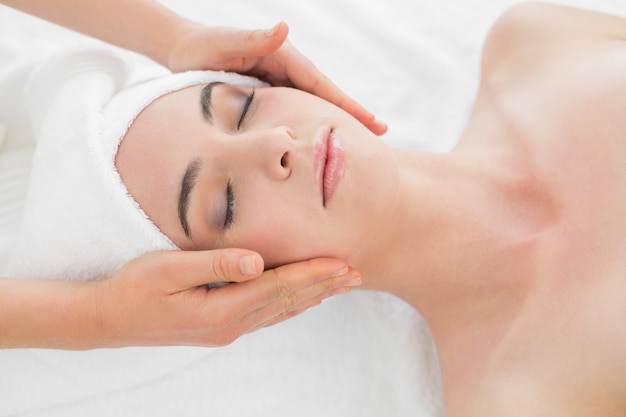 Hands massaging womans face at beauty spa